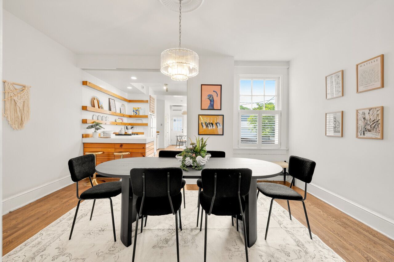 A modern dining room with a round table, black chairs, and a chandelier.