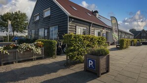 Un bâtiment à deux étages, doté d’un toit en pente, d’un panneau indiquant un espace de stationnement et d’une place de stationnement accessible aux personnes en fauteuil roulant.