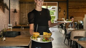 Un restaurant aux murs en bois et à la décoration moderne, avec notamment des luminaires suspendus.