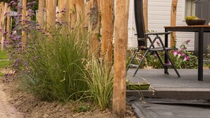 Une clôture en bois, une table avec des chaises et un bâtiment en arrière-plan.