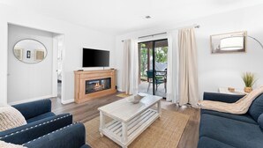 Een moderne woonkamer met een open haard, een flatscreen televisie en een groot raam met gordijnen.