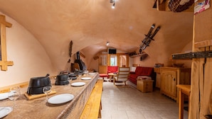 Una cocina acogedora y rústica con una encimera de madera larga, una chimenea y un comedor con un sofá rojo.
