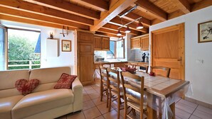 Ein gemütliches Interieur mit Essbereich, Holzbalkendecke und Blick ins Freie.