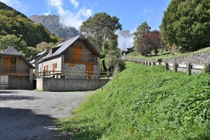 A stone building with wooden balconies, a gravel path, and a fence.