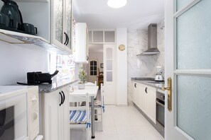 Une cuisine avec des meubles blancs, un four à micro-ondes, une cuisinière et un coin repas comprenant une table et des chaises.