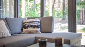 Ein modernes Wohnzimmer mit einem grauen Sofa, einem gemusterten Zierkissen und einer Kerze auf einem Tisch.