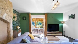 Un salon moderne avec un canapé, un téléviseur et une vue sur une terrasse extérieure.
