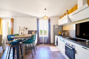 Une cuisine moderne avec un coin repas, comprenant une table ronde, des tabourets de bar et un four encastré.