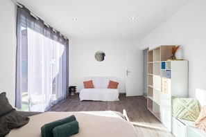Une chambre à coucher comprenant un lit, un canapé, une armoire et une grande fenêtre avec des rideaux.