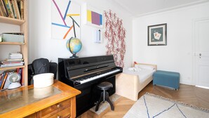 A room with a piano, a globe, a bookshelf, and a bed.