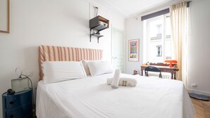 A neatly made bed with white linens, a striped headboard, and a folded towel on the bed.