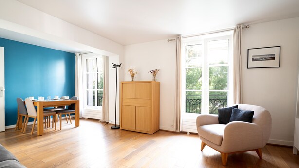 A spacious living area with a dining table, a sofa, a wooden cabinet, and a chair.