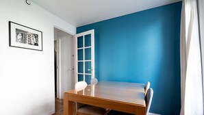 A dining area with a wooden table and chairs, a blue accent wall, and a door leading to another room.