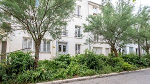 A residential building with multiple windows and balconies, surrounded by lush greenery and trees.