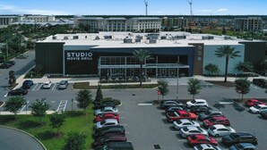 A multi-story building with a 'STUDIO MOVIE GRILL' sign, parking lot, and surrounding greenery.
