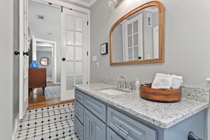 A bathroom with a sink, mirror, and wooden vanity. - The Lemonade Stand - the PERFECT location in Ocean Springs. Walk to downtown! (Ocean Springs)