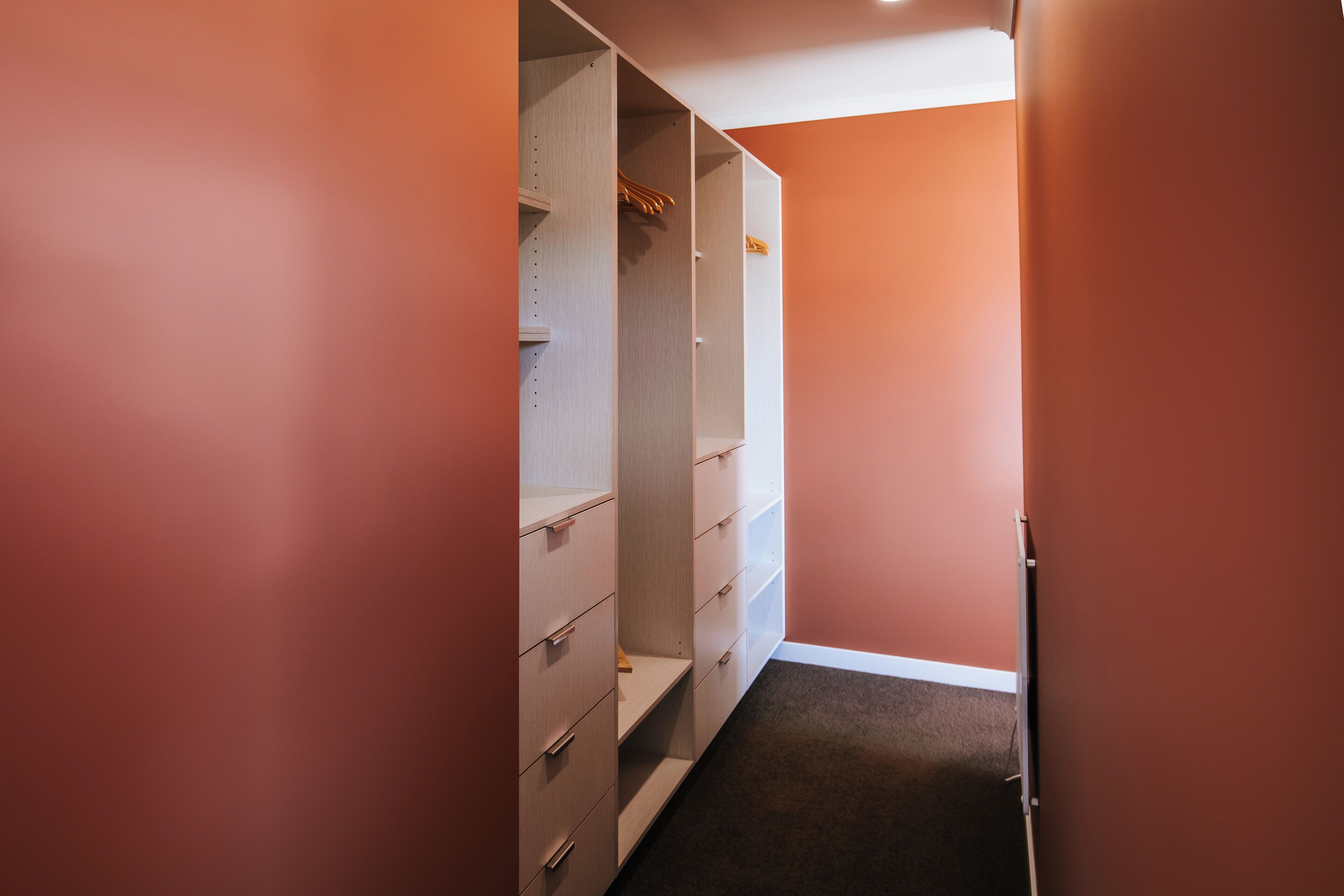Ein schmaler Flur mit einem Schrank, der offene Regale und Schubladen enthält.