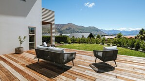 A modern outdoor patio with two black wicker sofas, a potted plant, and a view of mountains in the background. - Penshurst - Lake Views - Sleeps 8 (Wanaka)