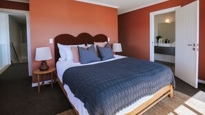 A bedroom with a large bed, two bedside tables, a nightstand, and a wardrobe. - Penshurst - Lake Views - Sleeps 8 (Wanaka)