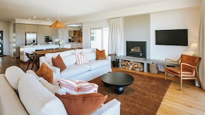 A modern living room with a sofa set, a coffee table, and a fireplace. - Penshurst - Lake Views - Sleeps 8 (Wanaka)