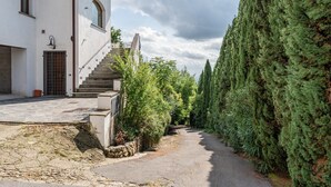 Ein Gebäude mit einer Treppe, die zu einer Tür führt, umgeben von Grünpflanzen und einem schmalen Pfad.