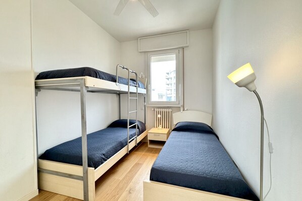 A small, well-lit room with bunk beds, a bedside table, and a lamp.