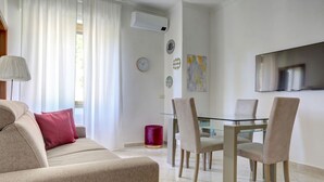 A modern living room with a beige sofa, a glass dining table, and matching chairs. - Vatican Apt Doria 64 - Home and More (Roma)