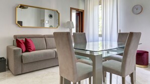 A modern living room with a glass-top dining table, beige sofa, and matching chairs. - Vatican Apt Doria 64 - Home and More (Roma)