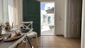 Un coin repas avec une table dressée pour deux personnes, une chaise et une vue sur l’extérieur.
