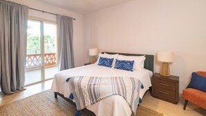 Een slaapkamer met een bed, twee nachtkastjes, een ventilator in het plafond en uitzicht op een balkon.