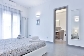 A modern hotel room with a bed, a bathroom, and a view of the city.