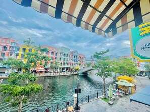 A riverside promenade with colorful buildings, a bridge, and outdoor seating areas. - Haleeda Homestay Grand World Phu Quoc (Phu Quoc)