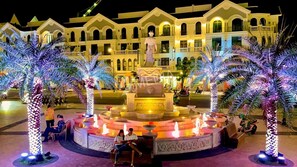 A fountain with multiple tiers and a statue on top, surrounded by palm trees with lights. - Haleeda Homestay Grand World Phu Quoc (Phu Quoc)
