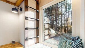 Une pièce chaleureuse avec une grande fenêtre, une étagère en bois et un tapis à motifs.