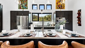A modern kitchen with dark cabinets, stainless steel appliances, and a central island with seating. - Beautiful Views Of Cathedral Rock, Hot Tub, Fire Pit, Wildlife Sightings, And Stargazing (Sedona)