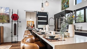 A modern kitchen with a long island, leather bar stools, pendant lighting, and a large window. - Beautiful Views Of Cathedral Rock, Hot Tub, Fire Pit, Wildlife Sightings, And Stargazing (Sedona)