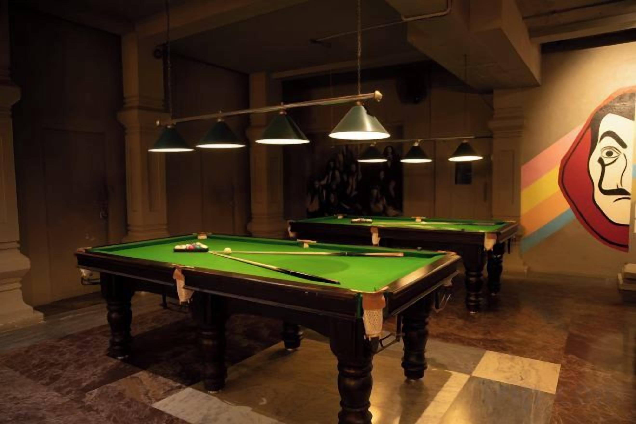 A pool table with a checkered floor, overhead lighting, and a mural on the wall.