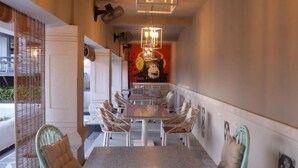 A dining area with a table and chairs, a hanging light fixture, and a wall with a poster. - Hotel FORT28 (Nagpur)