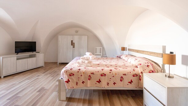 A bedroom with a bed, a TV, a desk, and a lamp. - Apartment 'Corte Nonna Mmela' with Private Terrace, Wi-Fi and Air Conditioning (melendugno)