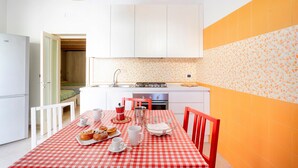 A compact kitchen with white cabinets, a red and white checkered tablecloth, and a breakfast setup. - Apartment 'Corte Nonna Mmela' with Private Terrace, Wi-Fi and Air Conditioning (melendugno)