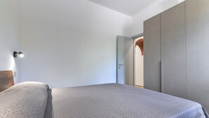 Une chambre à coucher comprenant un lit, une armoire et une porte donnant sur une autre pièce.