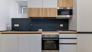 Une cuisine moderne équipée d’un four encastré, d’un four à micro-ondes et d’une machine à café posée sur le plan de travail.