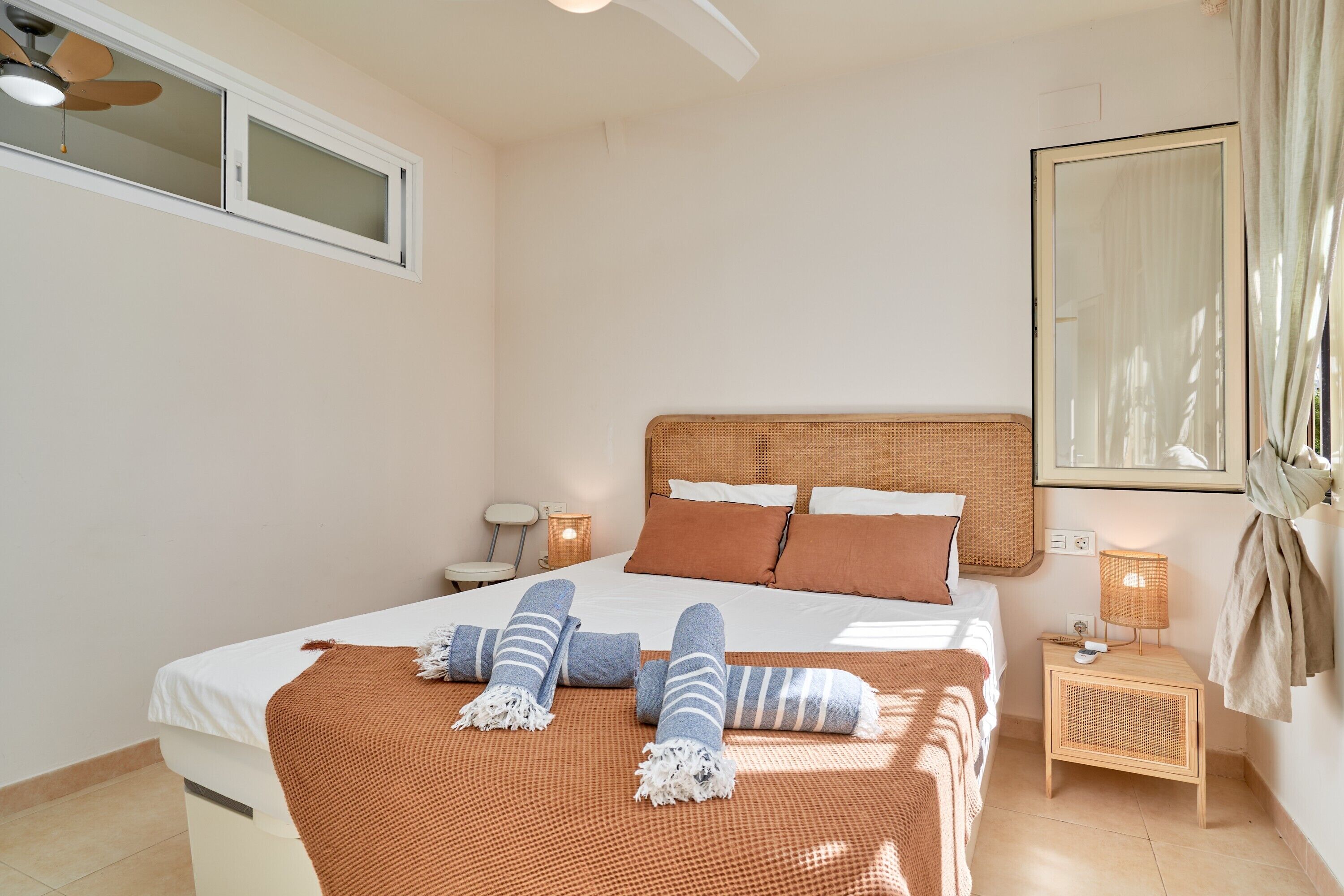 A bedroom with a bed, bedside table, lamp, and a window.