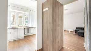 A modern apartment with a kitchen, a wooden wardrobe, a living area with a sofa and a coffee table, and a view through a window. - Nowolipki Standard Studio (Warszawa)