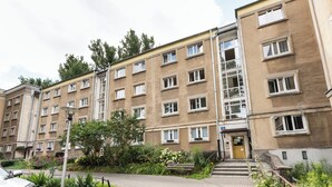 A multi-story residential building with a central entrance, surrounded by a landscaped garden with benches and flowers. - Nowolipki Standard Studio (Warszawa)