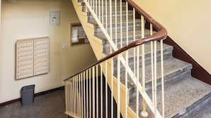 A spiral staircase with a wooden handrail and stone steps, leading to a door with a sign above it. - Nowolipki Standard Studio (Warszawa)