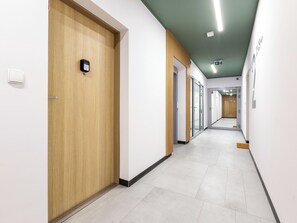 Un corridoio moderno con porte in legno, pavimento piastrellato di colore chiaro e soffitto verde.