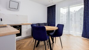 Una cocina moderna con encimera de madera, armarios blancos y un comedor con una mesa redonda y sillas azul oscuro.