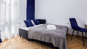 Un dormitorio moderno con cama, una silla y ventana con cortinas.