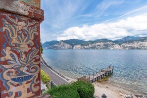 A waterfront view with a pier extending into the water, surrounded by mountains and a clear sky.